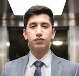 Confident man in a gray suit standing in an elevator with a briefcase, exuding professionalism.