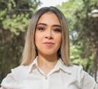 A confident woman poses outdoors in a park in Ciudad de México, wearing business casual attire.