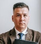 Portrait of a confident professional man holding a notebook, standing indoors.