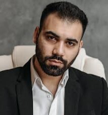 A serious lawyer in a black suit working diligently at his office desk.
