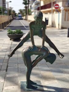 Inicio Outdoor bronze sculptures depicting children playing leapfrog on a sunny street.