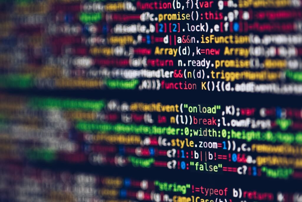 "¿Quién controla al algoritmo? Vivid, blurred close-up of colorful code on a screen, representing web development and programming.