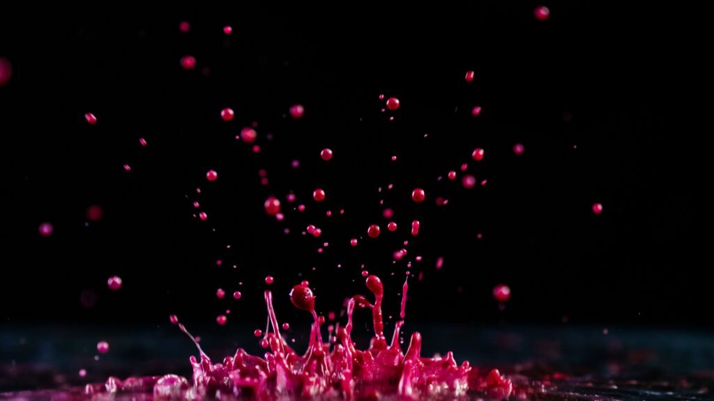 Dynamic red paint splash against a dark backdrop, capturing motion and vibrant color.