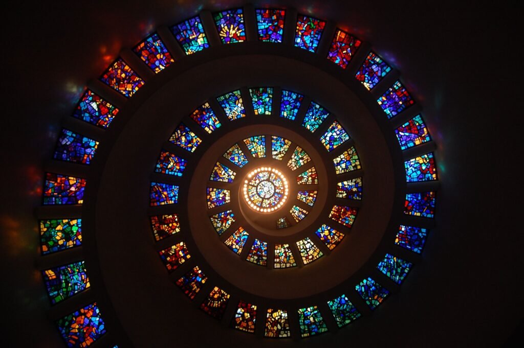 Del Panóptico a los Algoritmos: la vigilancia permanente en el siglo XXI Captivating spiral stained glass art with vibrant colors forming a dramatic eye-catching pattern.