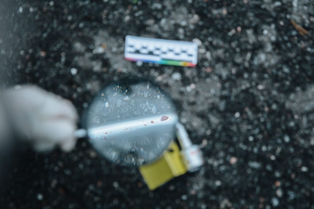 Close-up of evidence analysis at a crime scene with a magnifying glass.