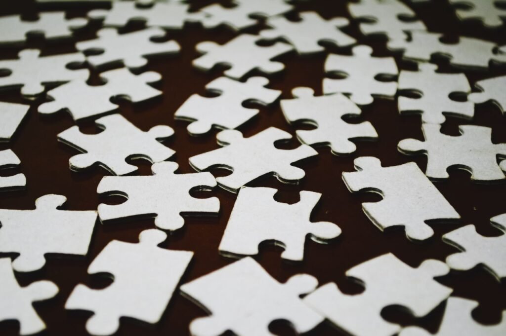 Detailed close-up view of scattered white jigsaw puzzle pieces on a dark surface.